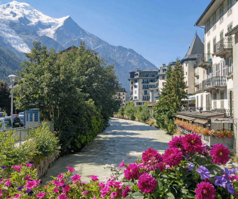 Scenic view of Chamonix in Haute Savoie, France, with the towering peaks of the Mont Blanc massif in the background, showcasing a charming alpine village nestled in the valley, surrounded by lush green landscapes and snow-capped mountains.