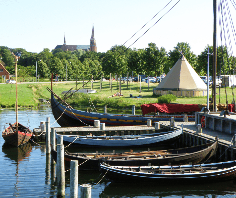 Scenic view of Roskilde, Denmark, featuring the Viking Ship Museum along the waterfront and traditional Danish architecture in the background.