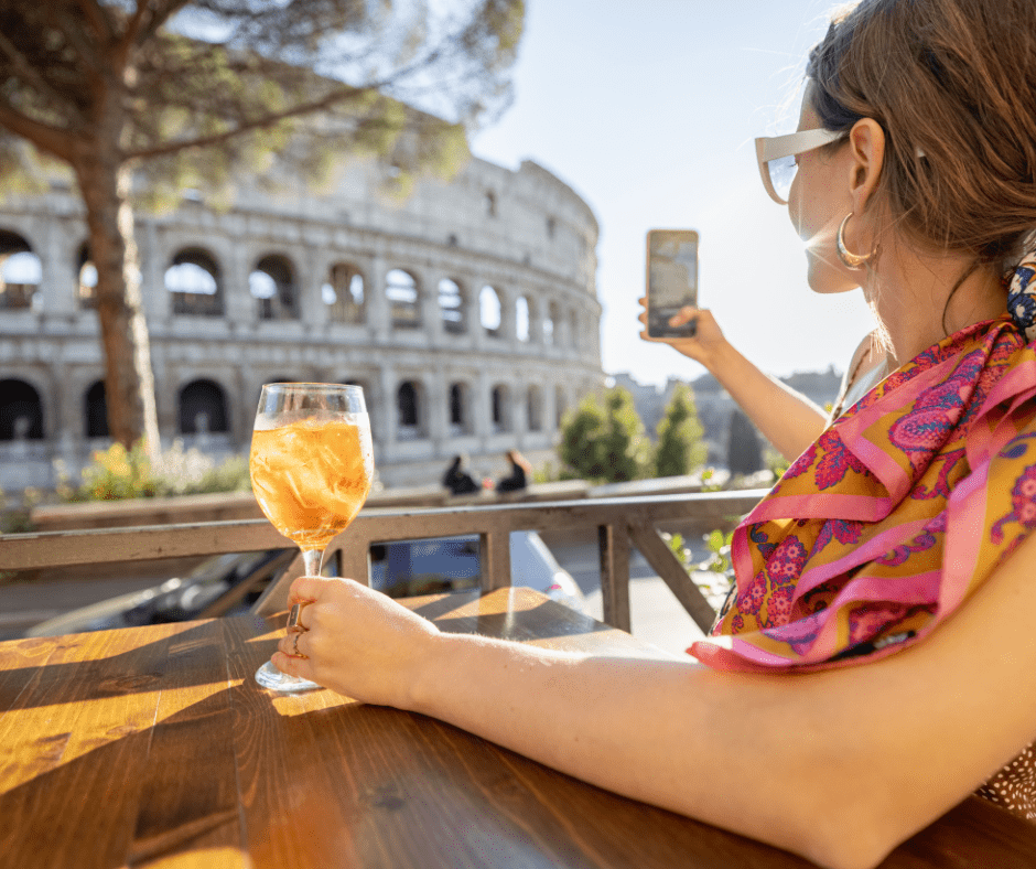 woman drinking spritz aperol at outdoor cafe near coliseum, the most famous landmark in Rome