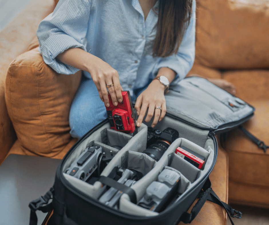 Woman packing camera equipment into a travel bag, preparing for a photography trip.